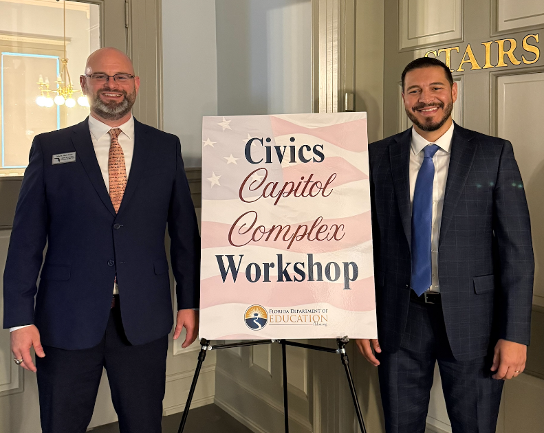 Mark Harrison, 2026 Florida Teacher of the Year, and Commissioner of Education Anastasios Kamoutsas pose in front of sign stating Civics Capitol Complex Workshop.